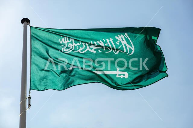 Saudi Arabia flag, National symbol waving against clear blue sky, sunny day