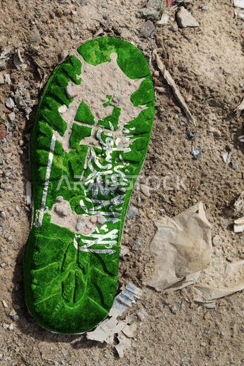 يظهر علم المملكة العربية السعودية على نعل حذاء قديم. يرمز هذا إلى مفهوم بيئي يتمثل في التلوث البيئي الناتج عن النفايات المنزلية والصناعية.