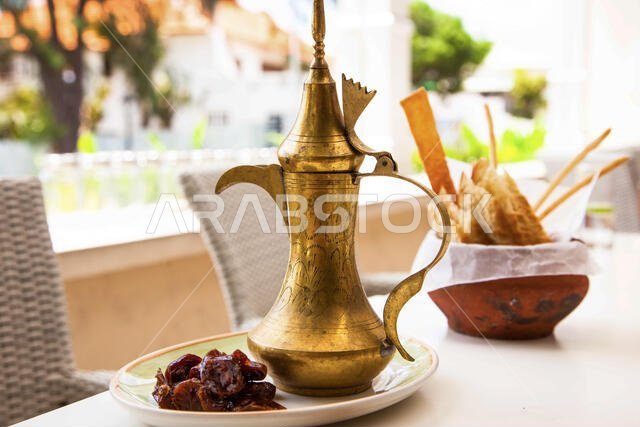 قهوة عربية في إبريق تركي تقليدي مع تمر ومقبلات في إناء فخاري