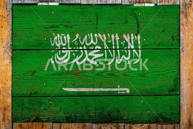 علم المملكة العربية السعودية على خلفية جدار خشبي. يرمز هذا العلم إلى الفخر الوطني ورمز الدولة. العلم مرسوم على سياج خشبي.