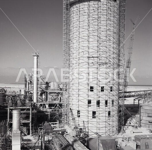 1960s, Saudi Arabia, out in the desert,a new tower being built at an oil refinery. 1960s, Saudi Arabia, out in the desert,a new tower being built at an oil refinery.