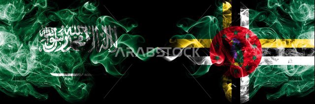 أعلام المملكة العربية السعودية ودومينيكا الدخانية الغامضة موضوعة جنبًا إلى جنب. أعلام دخانية حريرية سميكة الألوان تمثل الدول العربية والعربية والدومينيكية