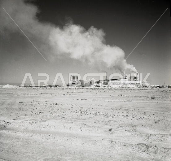 1960s historical, distant view of a fertiliser factory in the desert, Saudi Arabia, showing smoke coming from the industrial complex. The barren, arid soil meant that there was a huge need for fertilisers to enrich the farming land that would be developed around the regions springs. 1960s historical, distant view of a fertiliser factory in the desert, Saudi Arabia, showing smoke coming from the industrial complex. The barren, arid soil meant that there was a huge need for fertilisers to enrich the farming land that would be developed around the regions springs.