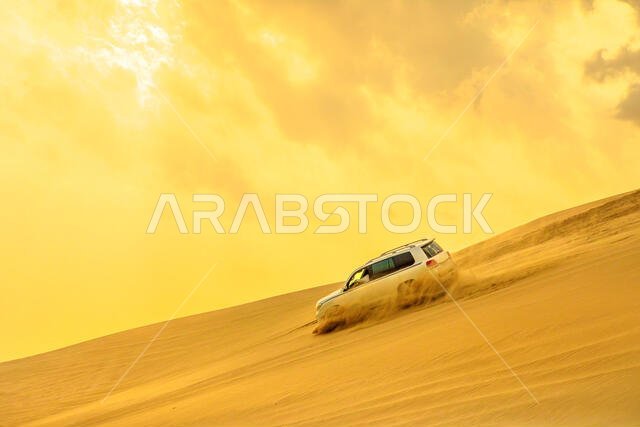 التزلج على الكثبان الرملية عند غروب الشمس بالقرب من قطر والمملكة العربية السعودية. خور العديد، الخليج العربي، الشرق الأوسط. يُعد هذا البحر الداخلي وجهة سياحية رئيسية في قطر.