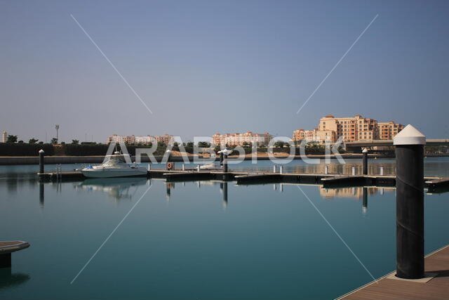 A small Yatch at small dock or harbour in an Inlet from the sea with calm reflecting water with buildings far away. Relaxing place in KAEC.