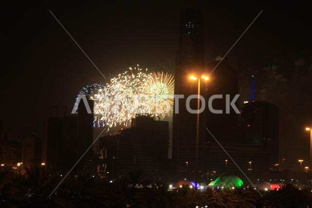 ألعاب نارية في عيد الفطر بمدينة الرياض بالقرب من مركز الملك عبد الله المالي، مع أضواء من مدينة الملاهي الشتوية وإطلالة من شارع الملك فهد.