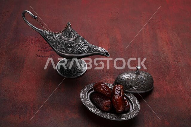 Silver plate with dates  and aladdin lamp on dark red wooden background. Ramadan background. Ramadan kareem.