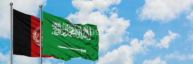 يرفرف علم أفغانستان وعلم السعودية معاً في مهب الريح أمام سماء زرقاء صافية تتلألأ فيها الغيوم البيضاء. مفهوم الدبلوماسية، العلاقات الدولية.