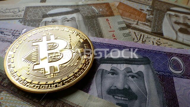 البيتكوين، عملة افتراضية على شكل عملة معدنية مادية، معروضة على الأوراق النقدية للريال السعودي