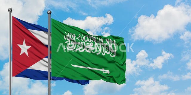 يرفرف علم كوبا وعلم السعودية معاً في مهب الريح أمام سماء زرقاء صافية تتلألأ بالغيوم البيضاء. مفهوم الدبلوماسية، العلاقات الدولية.