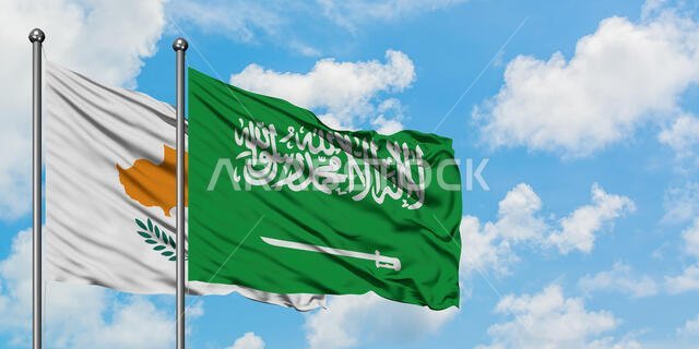 يرفرف علم قبرص والسعودية معاً في مهب الريح أمام سماء زرقاء صافية تتلألأ بالغيوم البيضاء. مفهوم الدبلوماسية، العلاقات الدولية.