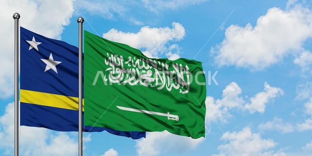 يرفرف علم كوراساو وعلم المملكة العربية السعودية معاً في مهب الريح أمام سماء زرقاء صافية تتخللها غيوم بيضاء. مفهوم الدبلوماسية، العلاقات الدولية.