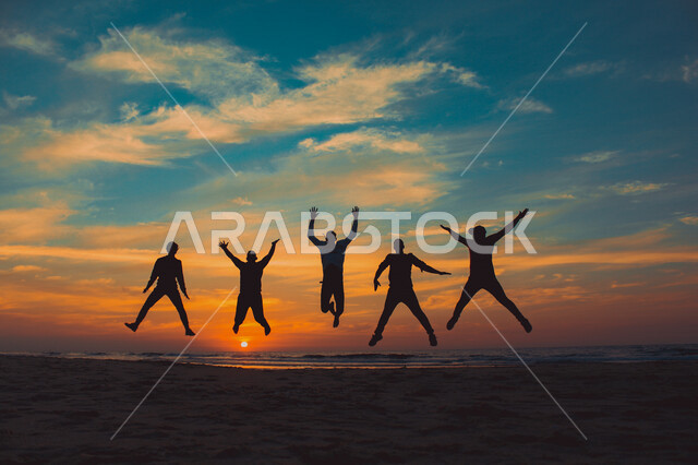 صورة ظلية لمجموعة من الاشخاص يقفزون على شاطيء البحر اثناء غروب الشمس، جمال الطبيعة، شاطئ البحر، المرح والترفيه، صورة ظلية