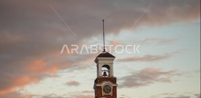 a clock tower at dusk and clouds rolling in.