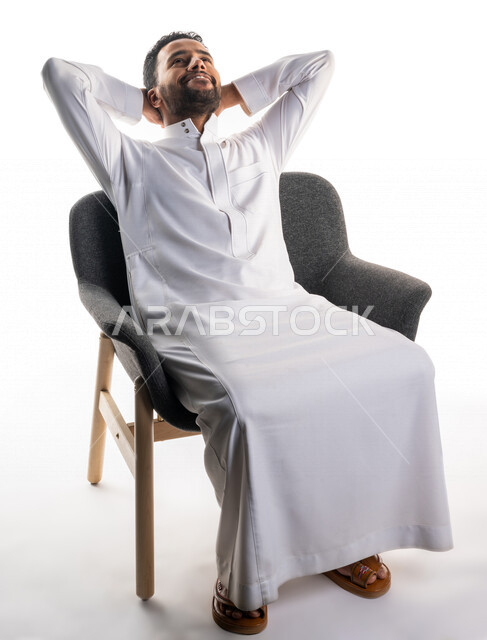 بورتريه لرجل عربي سعودي خليجي يرتدي الثوب السعودي يجلس على كرسي, إيماءات وجه ويدين تدل على الحاجه الى الراحه , الشعور بالتعب , النعاس و النوم, الإحساس بالإرهاق, الكسل والخمول, خلفية بيضاء 