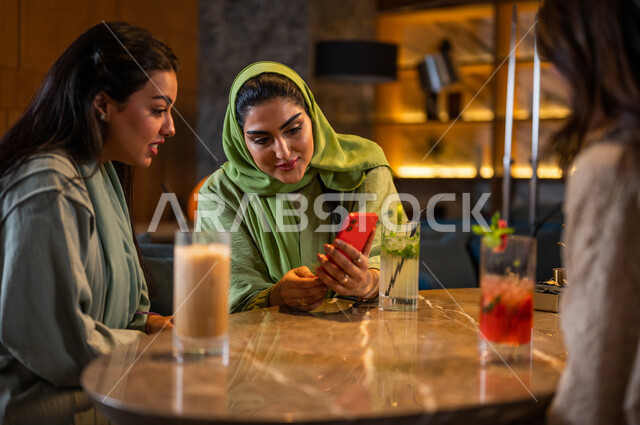 صديقات عربيات خليجيات سعوديات يجلسن في المقهى، إستخدام الهاتف المحمول، التسوق الالكتروني، علاقات إجتماعية بين الإصدقاء، إستخدام وسائل التواصل الإجتماعي، قضاء أوقات ممتعة مع الأصدقاء، تصفح الإنترنت، جلسة وناسة وتعارف