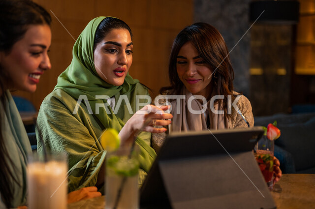 صديقات عربيات خليجيات سعوديات يجلسن في المقهى، إستخدام جهاز التابلت، التسوق الالكتروني، علاقات إجتماعية بين الإصدقاء، إستخدام وسائل التواصل الإجتماعي، قضاء أوقات ممتعة مع الأصدقاء، تصفح الإنترنت، جلسة وناسة وتعارف، كوفي شوب راقي بالسعودية