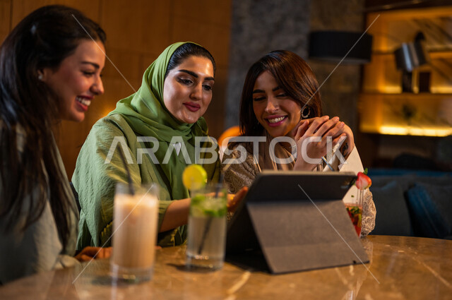 صديقات عربيات خليجيات سعوديات يجلسن في المقهى، إستخدام جهاز التابلت، التسوق الالكتروني، علاقات إجتماعية بين الإصدقاء، إستخدام وسائل التواصل الإجتماعي، قضاء أوقات ممتعة مع الأصدقاء، تصفح الإنترنت، جلسة وناسة وتعارف، كوفي شوب راقي بالسعودية