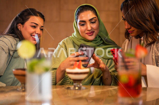 صديقات عربيات خليجيات سعوديات يجلسن في المقهى، توثيق اللحظات الجميلة بإستخدام الهاتف المحمول، علاقات إجتماعية بين الإصدقاء، إستخدام وسائل التواصل الإجتماعي، قضاء أوقات ممتعة مع الأصدقاء، جلسة وناسة وتعارف، فن وموهبة تصوير المأكولات والمشروبات