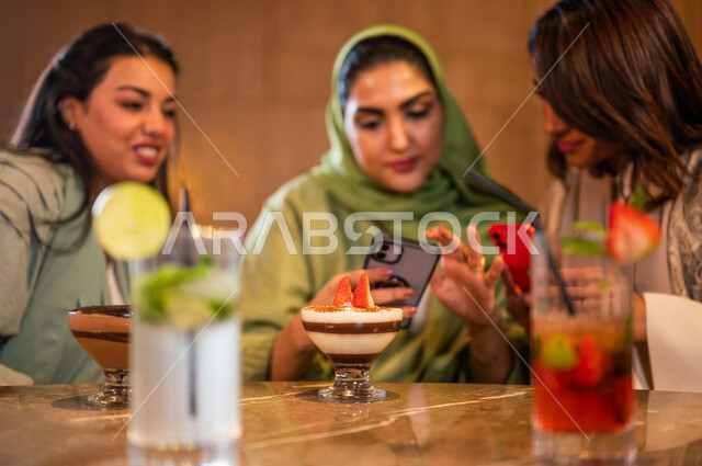 صديقات عربيات خليجيات سعوديات يجلسن في المقهى، توثيق اللحظات الجميلة بإستخدام الهاتف المحمول، علاقات إجتماعية بين الإصدقاء، إستخدام وسائل التواصل الإجتماعي، قضاء أوقات ممتعة مع الأصدقاء، جلسة وناسة وتعارف، فن وموهبة تصوير المأكولات والمشروبات