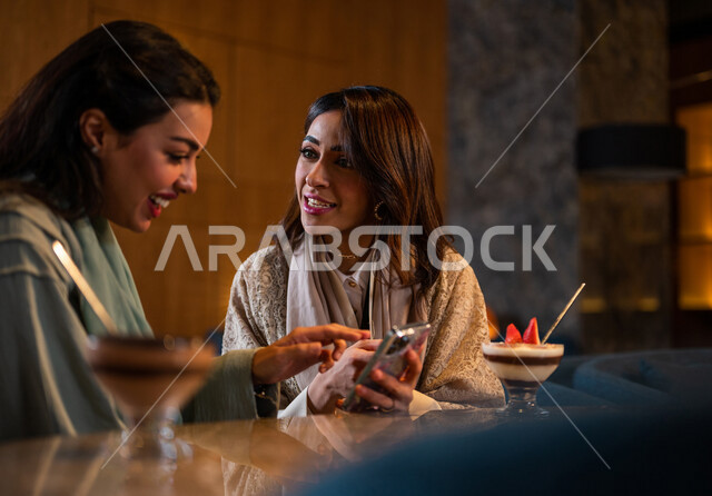 صديقات عربيات خليجيات سعوديات يجلسن في المقهى، إستخدام الهاتف المحمول، التسوق الالكتروني، علاقات إجتماعية بين الإصدقاء، إستخدام وسائل التواصل الإجتماعي، قضاء أوقات ممتعة مع الأصدقاء، تصفح الإنترنت، جلسة وناسة وتعارف