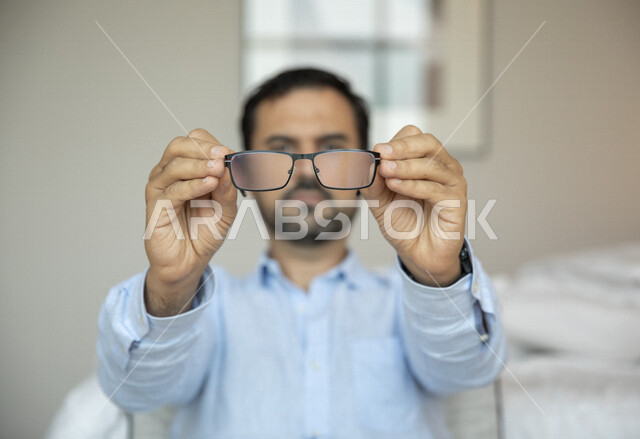 Arab man holding in his hand medical glasses for low vision, vision through medical glasses, concept of low vision, myopia