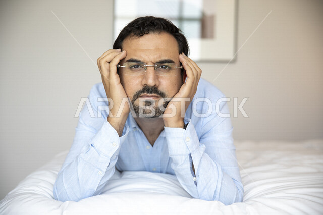 رجل عربي مستلقي على بطنه ، يرتدي النظارات الطبية خاصة بضعف النظر، النظر إلى الكاميرا ، الشعور بالضجر والملل ، الرؤية بالنظارات الطبية ، روتين ممل ، ضعف البصر