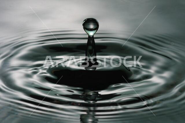 تساقط ثطرة من الماء على بقعة مائية، سطح مائي باللون الرمادي، شكل دائري رائع، خلفية لسطح مائي