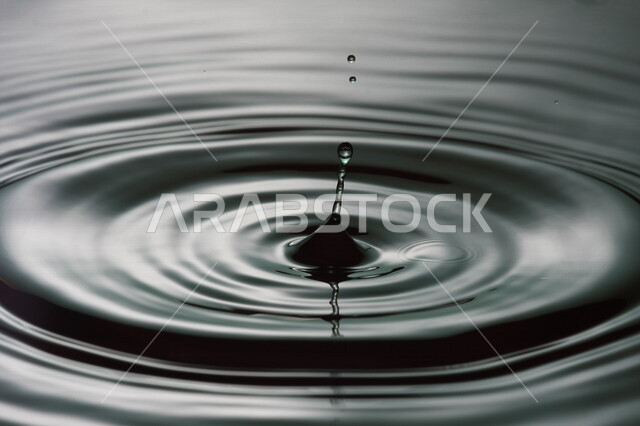 تساقط ثطرة من الماء على بقعة مائية، سطح مائي باللون الرمادي، شكل دائري رائع، خلفية لسطح مائي