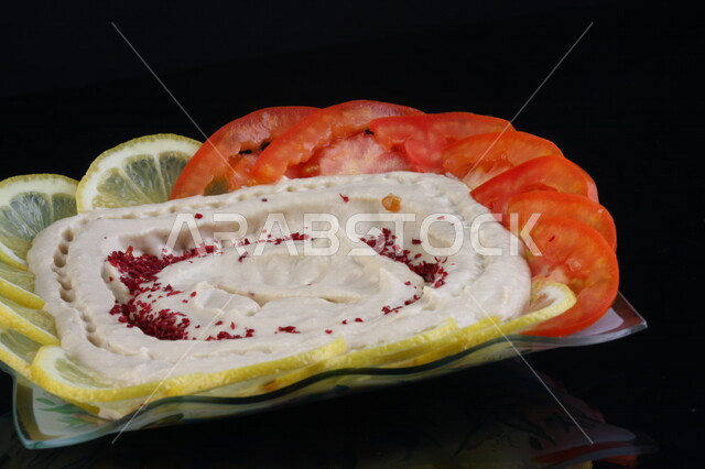 A plate of delicious chickpeas with tomato and lemon slices, traditional Arab dishes, Arab food, popular dishes, delicious recipes and food dishes, delicious healthy meals, oriental restaurants, hummus platter, restaurants for oriental Arabic food