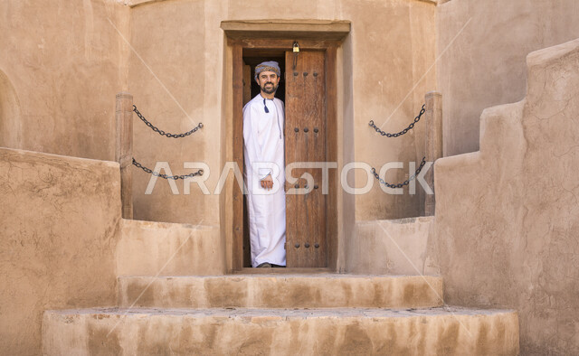 رجل عربي خليجي عماني يتجول في قلعة جبرين، رحلة سياحيه في احياء مدينة نزوى القديمة، معالم نزوى المشهورة، البيوت الشعبية التاريخية القديمة، منازل طينيه أثريه, السياحة في سلطنة عمان