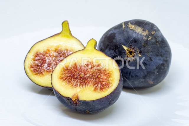 صورة مقربة لفاكهة التين الأسود اللذيذه على صحن أبيض، فاكهة التين المقطعه, مأكولات صحيه, محاصيل زراعيه