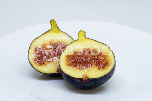 صورة مقربة لفاكهة التين الأسود اللذيذه على صحن أبيض، فاكهة التين المقطعه, مأكولات صحيه, محاصيل زراعيه