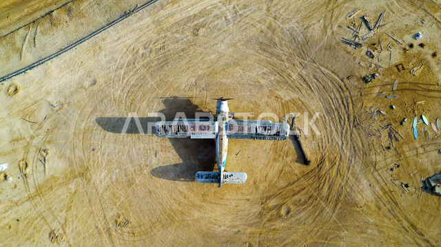 A picture from above of a crashed plane in the middle of the desert in Saudi Arabia, golden sands, desert nature in Saudi Arabia, sand dunes, a crashed plane