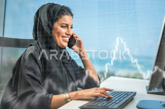 سيدة اعمال عربية خليجية سعودية تستخدم جهاز الحاسوب ، استخدام الهاتف النقال للتواصل مع الأصدقاء ، العمل داخل مقر الشركة ، انجاز مهام العمل ،تحقيق اهداف الشركة ، متابعة وتطوير العمل , رسومات بتقنية الهولوجرام .