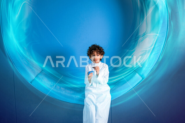 ولد عربي سعودي خليجي يقوم بأكل الحلوى الغير صحية , الحلويات والسكاكر , أطعمة مضرة بالصحة , خلفية ملونة .