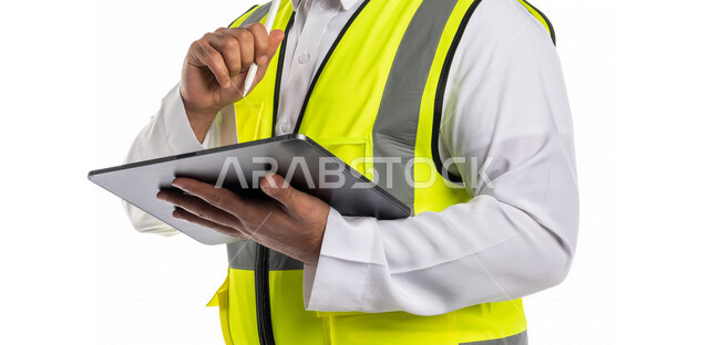 بورتريه لمهندس معماري عربي خليجي سعودي يرتدي سترة الوقايه الخاصه بالعمل، يستخدم جهاز التابلت, متابعة المشروع وتدقيق العمل, ادارة اعمال البناء ، اشراف ومتابعة، الرقابه على المشاريع, خلفيه بيضاء, هندسه معماريه