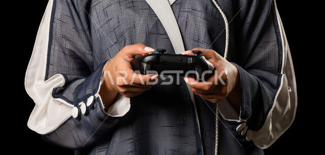 بورتريه لإمرأه عربيه سعوديه خليجيه تمسك بيدها عصا التحكم و تلعب بألعاب الفيديو، المتعة و التسلية بألعاب الفيديو، ألعاب البلايستيشن الترفيهية، تقنيات و ألعاب, قضاء وقت ممتع, خلفيه سوداء