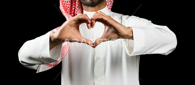 رجل عربي سعودي خليجي يشكل بيده شكل القلب، إيماءات يدين تدل على الحب والفرح والسعادة، أعياد ومناسبات، الشعور بالحب والغرام, مناسبات سعيدة, خلفية سوداء