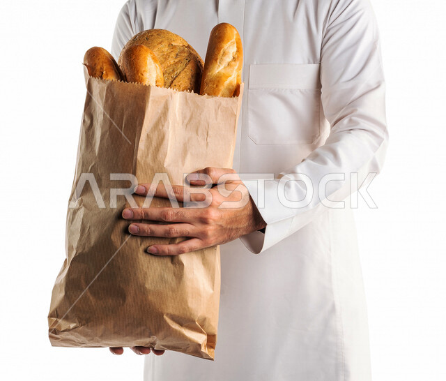 Portrait of a Saudi Arabian Gulf man wearing the Saudi thobe holding a bag of bread in his hand, enjoying shopping, delivery orders, home delivery services, online ordering, food delivery services, online orders, white background
