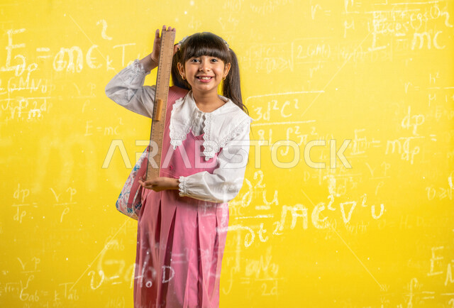 Portrait of a Saudi Arabian Gulf student holding a numbered ruler and wearing a school uniform, school backpack, stationery, preparing for the new school year, education in Saudi Arabia, back to school, yellow background