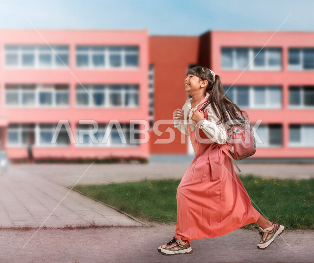 طالبة عربية خليجية سعودية ترتدي الزي المدرسي وتحمل حقيبة الظهر المدرسية، ايماءات وجه تدل على السعادة الشديدة، الذهاب الى المدرسة، الإستعداد للعام الدراسي الجديد، التعليم في السعودية، صورة الجسم بالطول الكامل، العودة إلى المدارس