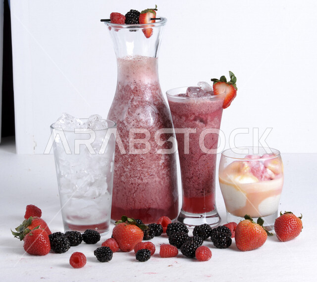 كوب من عصير الفواكه اللذيذ، مشروب بارد من الفواكه، مشروبات باردة، عصائر طبيعية لذيذة، عصير صحي ومفيد، كوكتيل صيفي منعش ومثلج، عصير التوت مع الفراولة، حبات من فاكهة التوت والفراولة، خلفية بيضاء