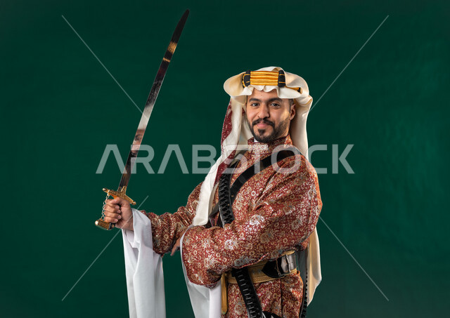 كروما، رجل عربي خليجي سعودي، ينظر إلى الكاميرا، يحمل بيده سيف طويل، يرتدي الزي الخليجي السعودي، الإحتفال بالعيد الوطني السعودية، هوية اليوم الوطني السعودي 92، خلفية خضراء، يوم التأسيس السعودي، زي تراثي سعودي للمناسبات الوطنية