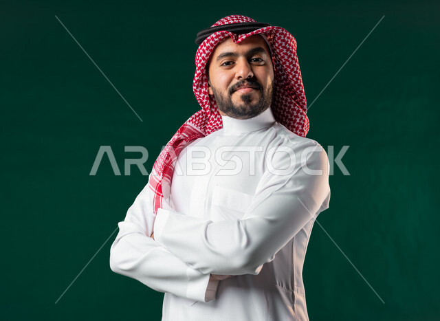 كروما، رجل عربي خليجي سعودي، ينظر إلى الكاميرا بأيدي متقاطعة، يرتدي الزي الخليجي السعودي التقليدي، الإحتفال باليوم الوطني السعودي، هوية اليوم الوطني السعودي 92، خلفية خضراء، يوم التأسيس السعودي، العيد الوطني السعودي