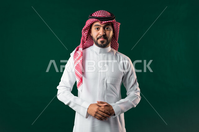 كروما، رجل عربي خليجي سعودي، ينظر إلى الكاميرا بأيدي متقاطعة، يرتدي الزي الخليجي السعودي التقليدي، الإحتفال باليوم الوطني السعودي، هوية اليوم الوطني السعودي 92، خلفية خضراء، يوم التأسيس السعودي، العيد الوطني السعودي