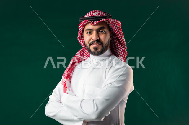 كروما، رجل عربي خليجي سعودي، ينظر إلى الكاميرا بأيدي متقاطعة، يرتدي الزي الخليجي السعودي التقليدي، الإحتفال باليوم الوطني السعودي، هوية اليوم الوطني السعودي 92، خلفية خضراء، يوم التأسيس السعودي، العيد الوطني السعودي