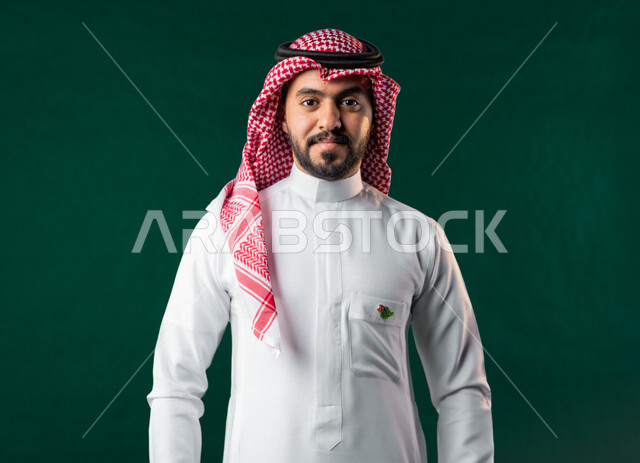 Karuma, Saudi Arabian Gulf Arab man looking at camera, wearing traditional Saudi Arabian dress, 2022 National Day logo on his chest, Saudi National Day celebration, Saudi National Day 92 ID, green background, Saudi founding day