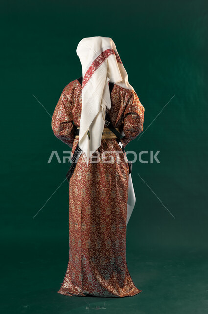 كروما من الخلف لرجل عربي سعودي خليجي، يرتدي الزي الشعبي التقليدي العريق, دقلة أهل المنطقه الوسطى مع المحزم والخنجر, الإحتفال باليوم الوطني السعودي، هوية اليوم الوطني السعودي 92، أزياء سعودية تراثية، يوم التأسيس، صورة الجسم بالطول الكامل, خلفيه خضراء
