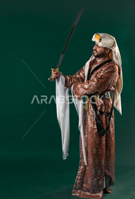 كروما لرجل عربي سعودي خليجي، يحمل السيف بيده, يرتدي الزي الشعبي التقليدي العريق, دقلة أهل المنطقه الوسطى مع المحزم والخنجر, الإحتفال باليوم الوطني، هوية اليوم الوطني السعودي 92، أزياء سعودية تراثية، يوم التأسيس، صورة الجسم بالطول الكامل, خلفيه خضراء